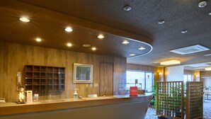 A reception area with a wooden counter, a framed picture on the wall, and a glass partition. - Tabist Business Hotel Osamura (Sabae)