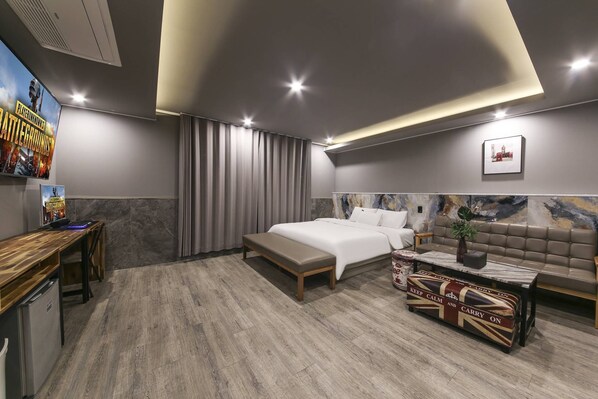 Una habitación de hotel moderna con una cama grande, un escritorio y un sofá.