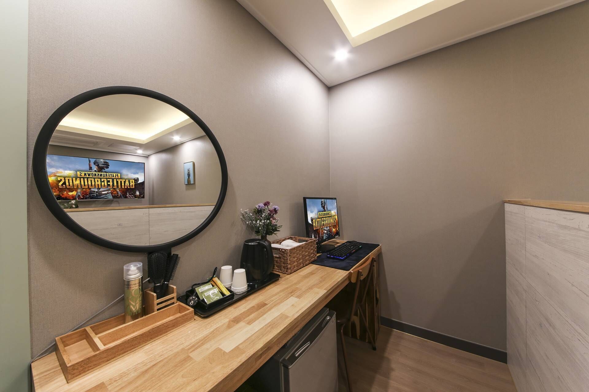 Een moderne badkamer met een houten wastafelmeubel, een ronde spiegel en twee posters aan de wand.