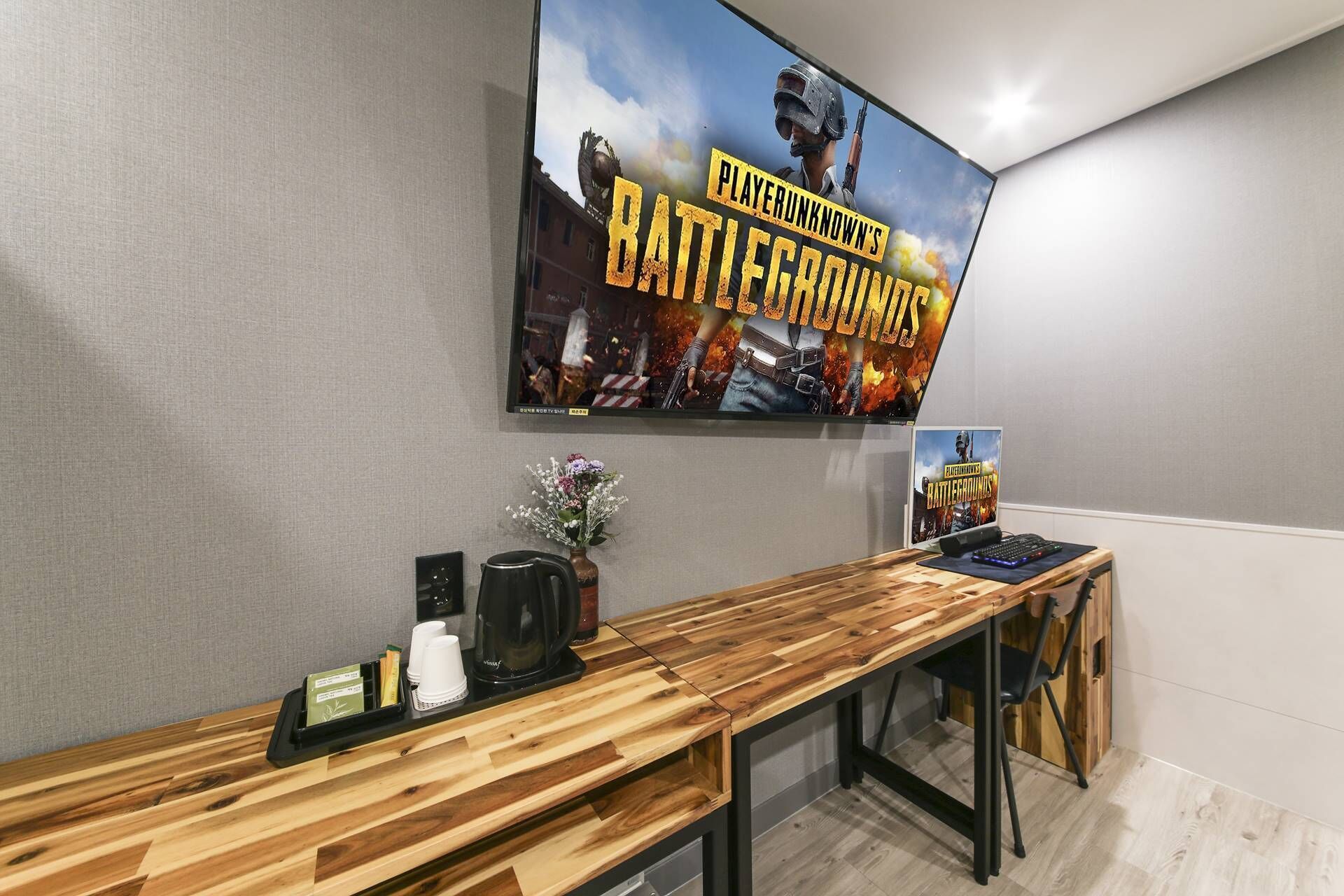 Un área de recepción con mostrador de madera, una máquina de café y un cartel de PUBG Mobile.