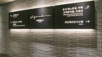 A wall with directional signs for various hotel amenities including a fitness area, PC game room, and a table tennis room.