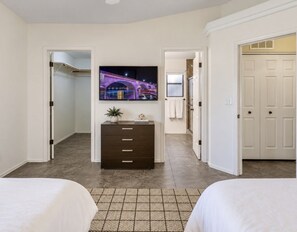 A hotel room with two beds, a dresser, a flat-screen TV, and a view of a bridge.