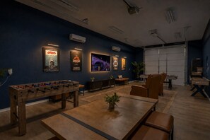 Ein Zimmer mit Tischfußballtisch, einer Sitzecke und Wandklimaanlagen.