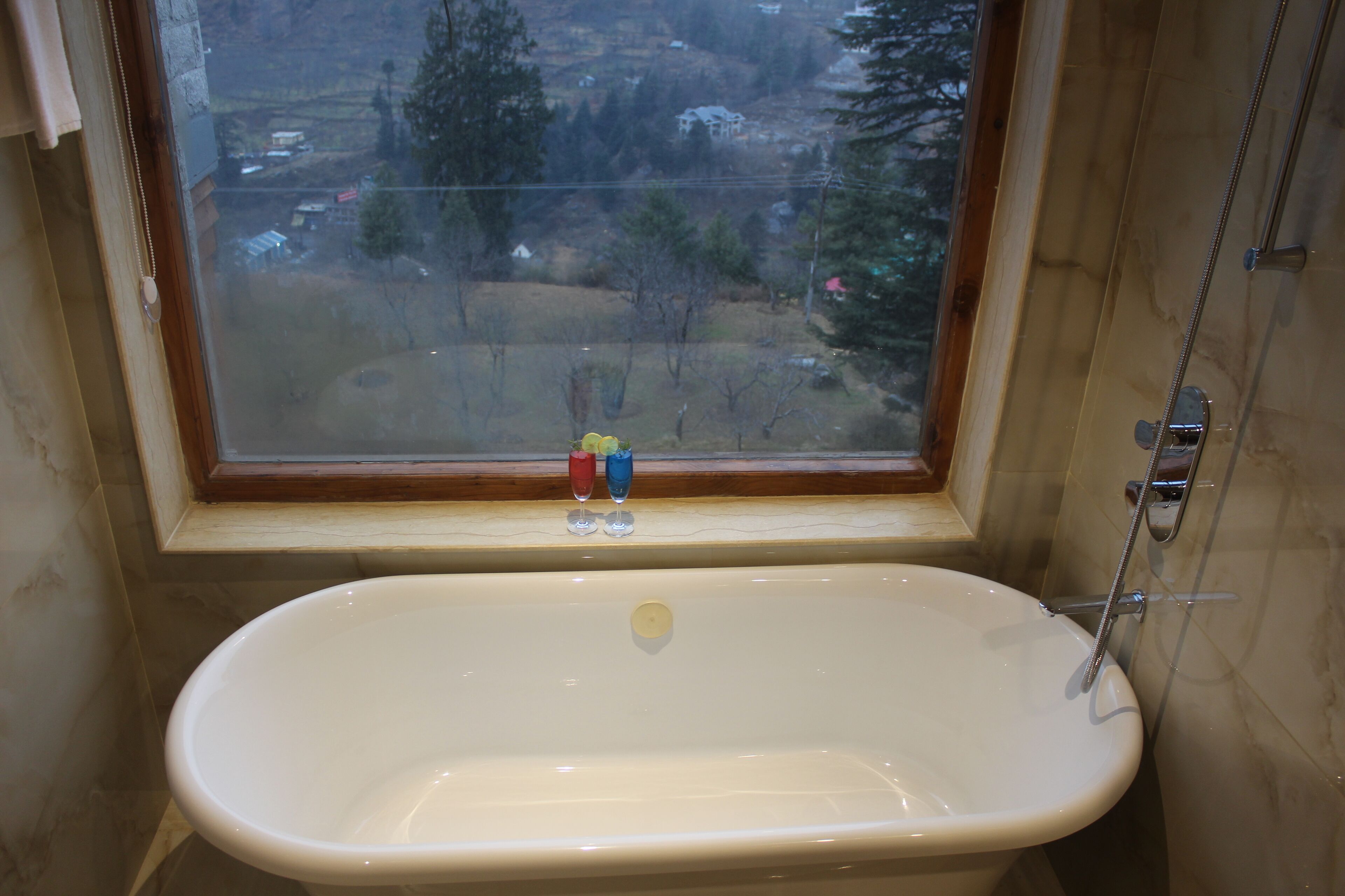 A bathroom with a bathtub, a window, and a shower.