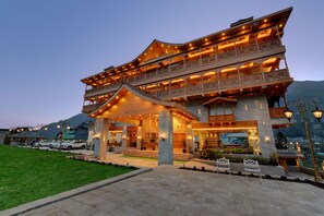 A multi-story hotel with a traditional architectural style, featuring balconies and a well-lit entrance. - Tiaraa Hotels & Resorts - A Luxury Resort Manali (Manali)
