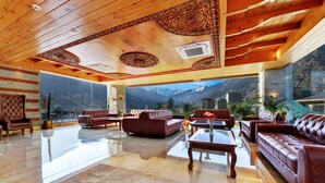 A spacious living area with leather sofas, a coffee table, and a large window offering a mountain view.