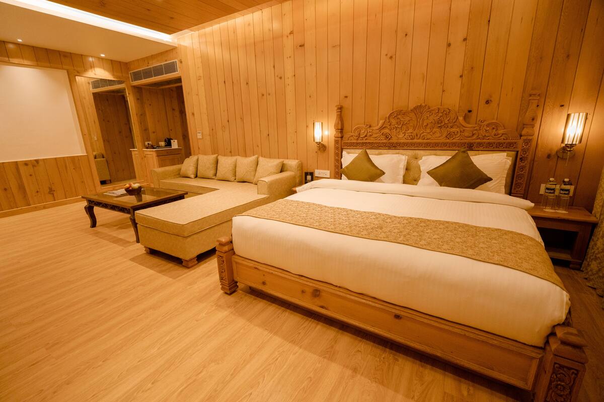 A wooden-paneled room with a large bed, a sofa, and a coffee table.