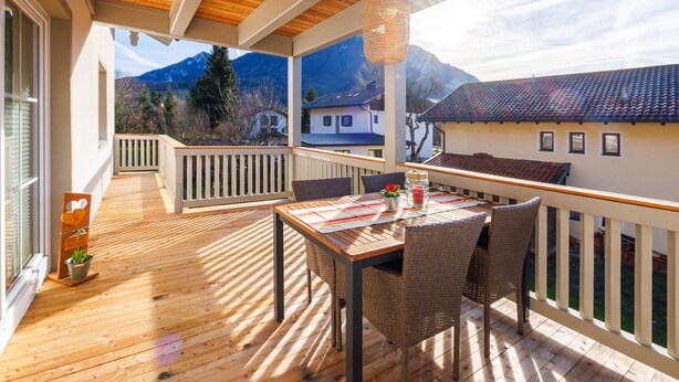 Eine Holterrasse mit Tisch und Stühlen, mit Blick auf eine Berglandschaft.