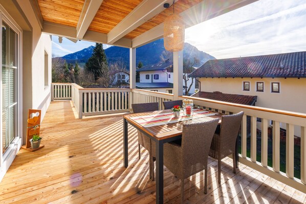 A wooden deck with a table and chairs, overlooking a mountain landscape.