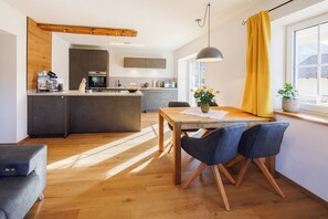 Una cocina moderna con una isla central, suelo de madera y un área de comedor con mesa y sillas.