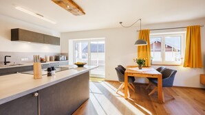 Eine moderne Küche mit einer zentralen Kochinsel, einem Holztisch und Stühlen.