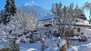 Eine verschneite Landschaft mit einem Haus und Bäumen.