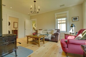 Een woonkamer met een bank, een rode fauteuil, een houten salontafel en een kroonluchter.