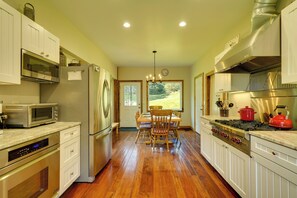 A kitchen with modern appliances, wooden flooring, and a view to the outdoors.
