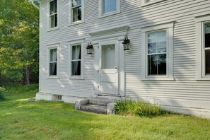 A white two-story house with a front door, two windows, and a small porch.