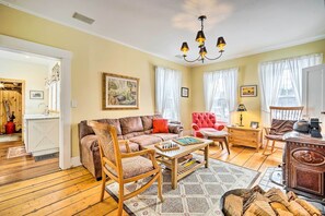 A cozy living room with a brown sofa, a red armchair, a wooden coffee table, and a vintage radio.