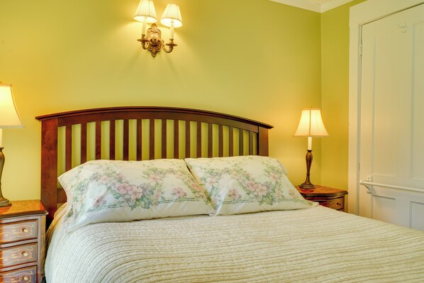 A bed with floral bedding, a wooden headboard, and two bedside lamps.