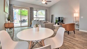 A modern living room with a round white table, two white chairs, a grey sofa, a brown armchair, a ceiling fan, and a TV. - Private Pool & Community Perks: Mesa Home! (Mesa)