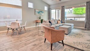A spacious living room with a grey sofa, a coffee table, and a dining area with chairs and a small table. - Private Pool & Community Perks: Mesa Home! (Mesa)
