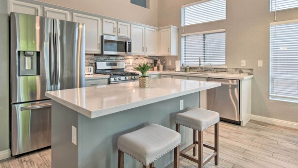 A modern kitchen with stainless steel appliances, a central island with stools, and a large window providing natural light. - Private Pool & Community Perks: Mesa Home! (Mesa)