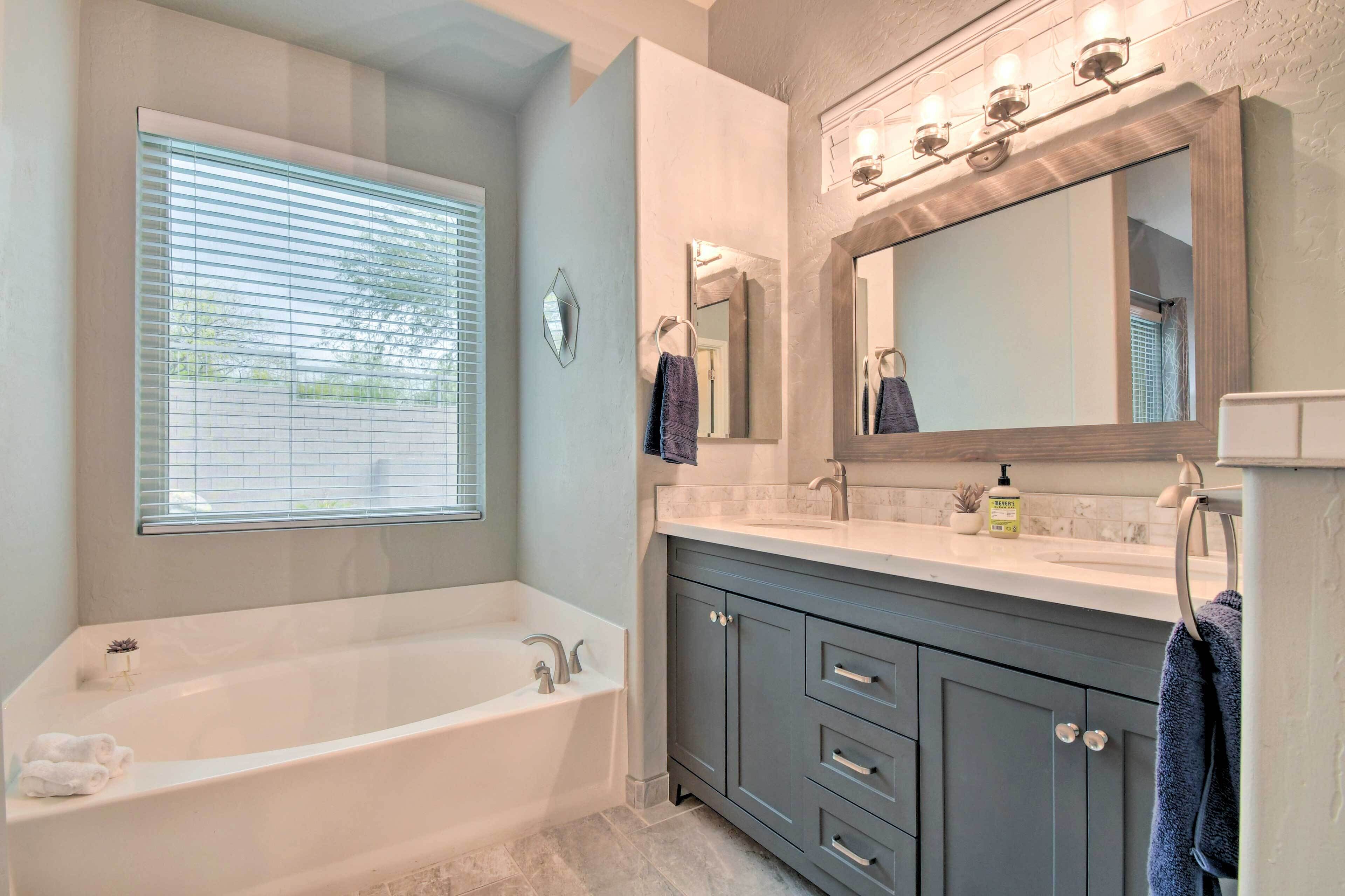 Une salle de bain moderne avec une baignoire, un meuble-lavabo et un grand miroir.