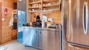 Eine moderne Küche mit Edelstahlgeräten, Holzregalen mit Gläsern und einem eingebauten Backofen.