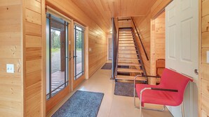 Ein Holzinnenraum mit Treppe, einem roten Sessel und einer Tür.