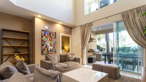 A modern living room with a beige sofa set, a white coffee table, and a colorful abstract art piece on the wall. - 1 Mile to Disney: Modern Townhouse in Magic 3114 (Kissimmee)