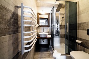 Enjoy a refreshing shower in the sleek bathroom with a glass-enclosed shower, standalone sink, and toilet.