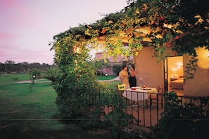 Enjoy a romantic dinner for two in this serene outdoor dining area, surrounded by a tranquil lawn and trees.