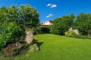 Un jardín bien cuidado con césped, rocas grandes y abundante follaje.