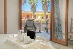 A balcony with a table set for two, a coffee maker, and a tablet on a tray.