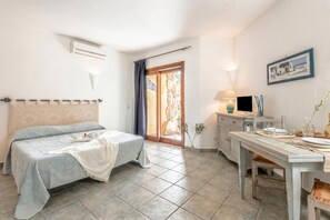 Quarto com cama, escrivaninha, cadeira, luminária e quadro na parede.