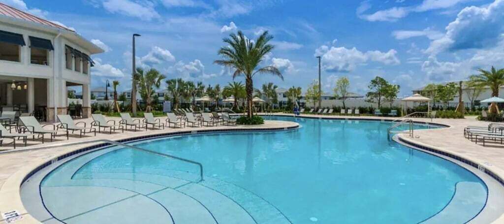 A large outdoor swimming pool with lounge chairs and palm trees.
