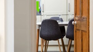 A dining area with two chairs and a table, a wooden door, and a white cabinet in the background. - Clifton Spacious 3 Bed Apt&Parking-Simply Check In (Bristol)