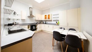 A modern kitchen with a central island, built-in oven, and a dining area with two chairs. - Clifton Spacious 3 Bed Apt&Parking-Simply Check In (Bristol)