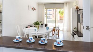 A dining area with a white table and chairs, a plant, and a view of the outside. - Jardines Family 204 by Interhome (Salou)