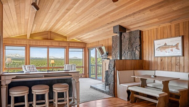 A wooden interior with a bar area, seating, and a fireplace.