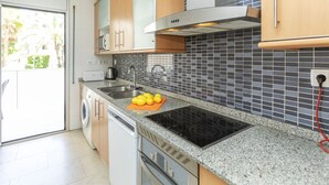 Una cocina moderna con encimeras de granito, estufa integrada, un fregadero y lavavajillas.