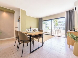 A dining area with a table set for four, a sofa, and a balcony with a view of buildings.