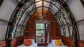 Quarto aconchegante com arco, duas camas, vigas de madeira e vista por uma porta.