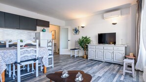 Een moderne woonkamer met een eethoek, een flatscreen-televisie en een potplant.