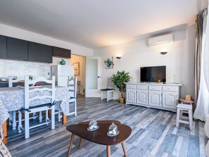 Una sala de estar moderna con comedor, un televisor de pantalla plana y una planta en maceta.