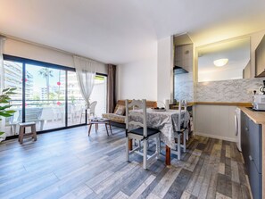 Una habitación de hotel moderna con balcón, zona de comedor y cocina.