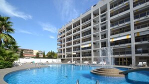 A multi-story hotel with a central swimming pool, surrounded by lounge chairs and a water fountain. - Michelangelo by Interhome (Salou)