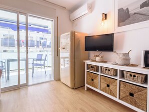 A modern room with a sliding glass door leading to an outdoor area, a built-in TV, and wicker baskets on a white shelf.