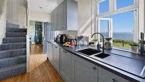 A kitchen with a large window, a sink, and a view of the sea. - Amazing views -  Woodburner - Wi-Fi (Torpoint)