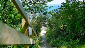A pathway leading through dense greenery towards a white structure with a view of the sea. - Amazing views -  Woodburner - Wi-Fi (Torpoint)