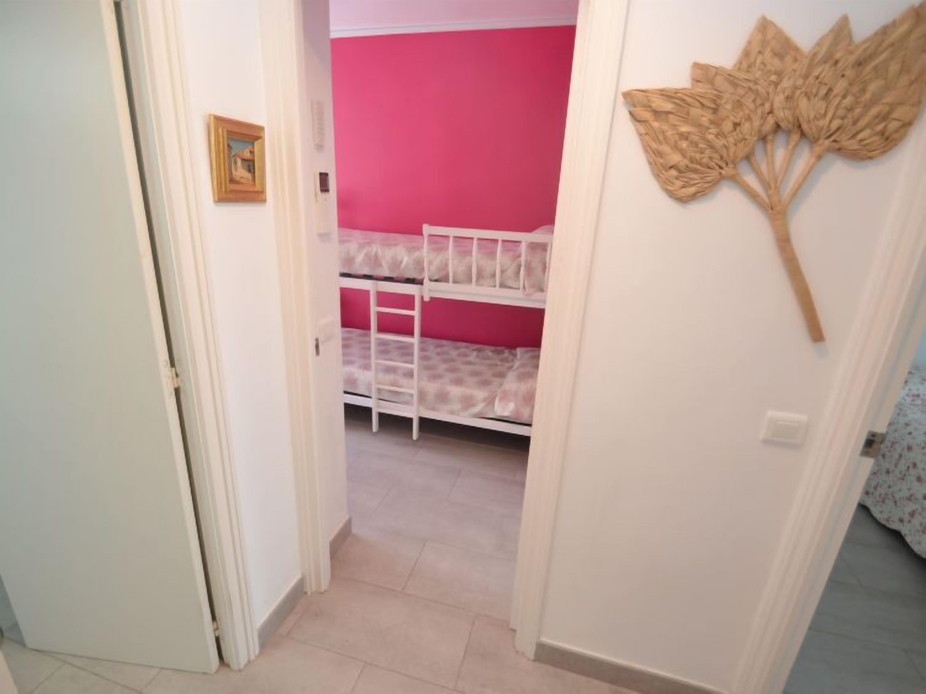 Een kamer met stapelbedden, een roze muur en een houten wanddecoratie.