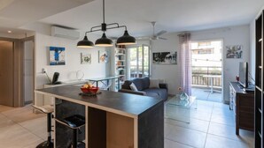 Una cucina moderna con isola centrale, sgabelli da bar, illuminazione a sospensione e vista all'esterno.